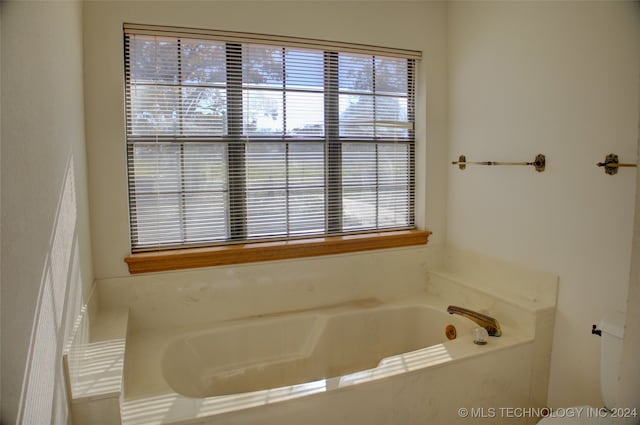 bathroom with tiled tub and a wealth of natural light