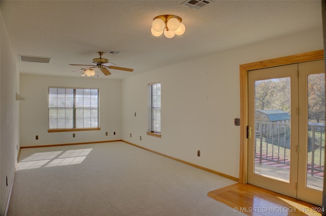 carpeted empty room featuring ceiling fan and a textured ceiling