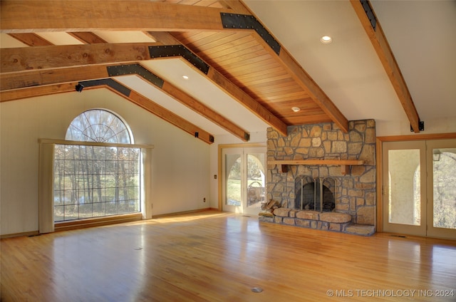 unfurnished living room featuring beam ceiling, a fireplace, plenty of natural light, and hardwood / wood-style floors