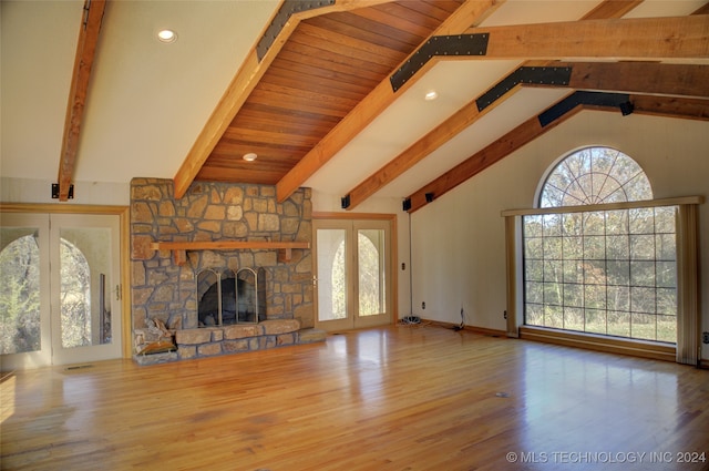 unfurnished living room with hardwood / wood-style floors, beam ceiling, a fireplace, and french doors