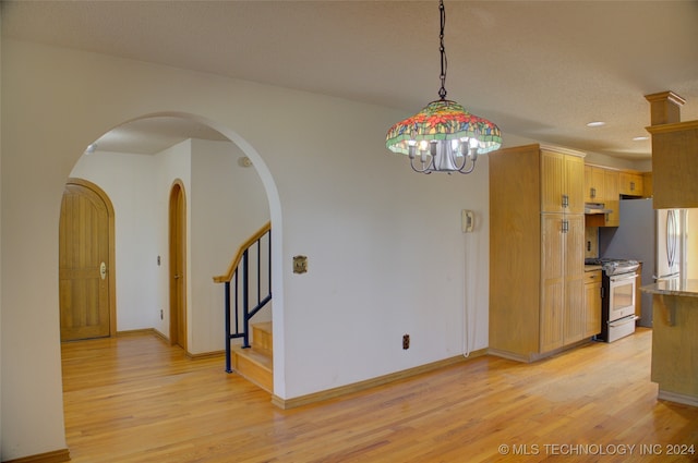 kitchen featuring light brown cabinetry, light wood-type flooring, gas range gas stove, and pendant lighting