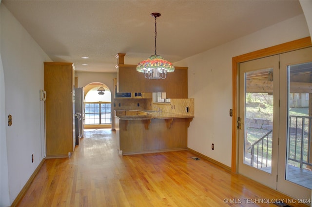 17808 S 129th E Ave, Bixby, OK 74008 - kitchen with a peninsula, a breakfast bar, light wood-style floors, baseboards, and brown cabinets