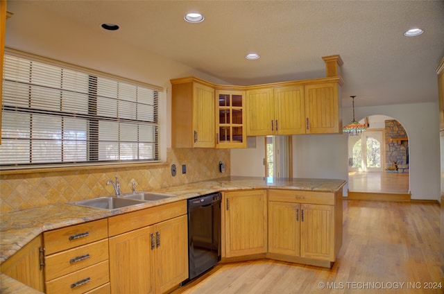 kitchen featuring dishwasher, sink, kitchen peninsula, light hardwood / wood-style floors, and pendant lighting