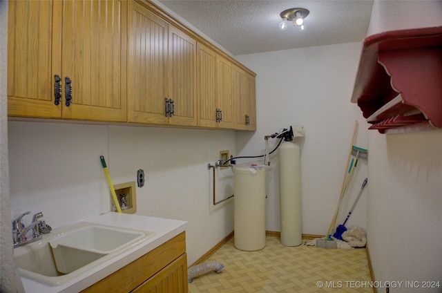 laundry room featuring cabinets, washer hookup, a textured ceiling, and sink