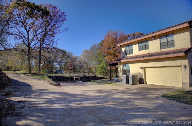 17808 S 129th E Ave, Bixby, OK 74008 - view of side of home featuring an attached garage, central air condition unit, stucco siding, driveway, and a tile roof