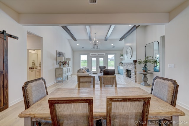 dining room featuring vaulted ceiling with beams, a barn door, light hardwood / wood-style floors, and an inviting chandelier