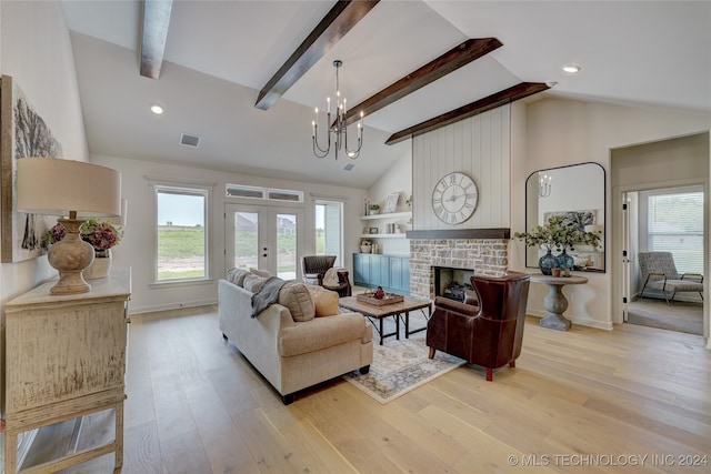 living room featuring vaulted ceiling with beams, a stone fireplace, light hardwood / wood-style floors, and an inviting chandelier