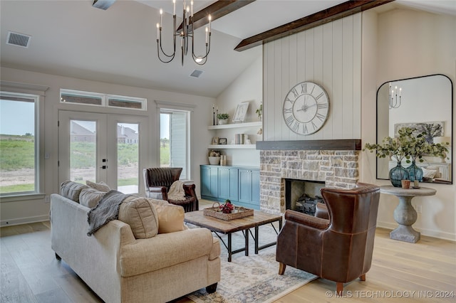 living room with plenty of natural light, light hardwood / wood-style floors, a stone fireplace, and lofted ceiling with beams