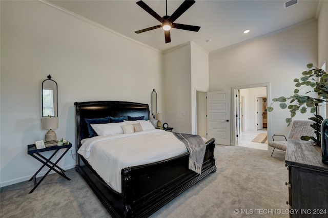 bedroom with ceiling fan, crown molding, a towering ceiling, and light carpet