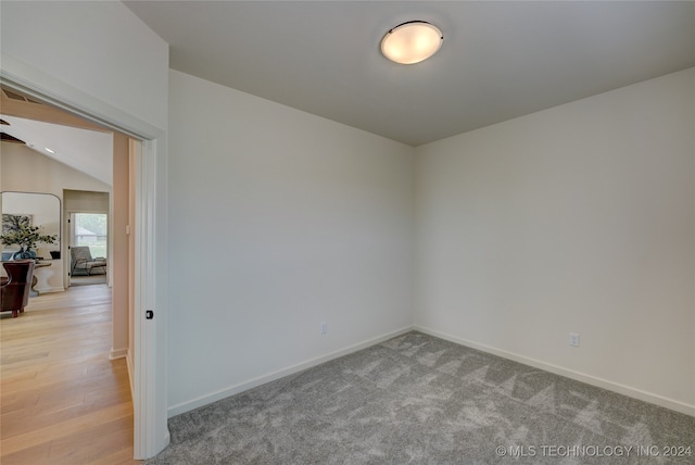 spare room with vaulted ceiling and light hardwood / wood-style flooring