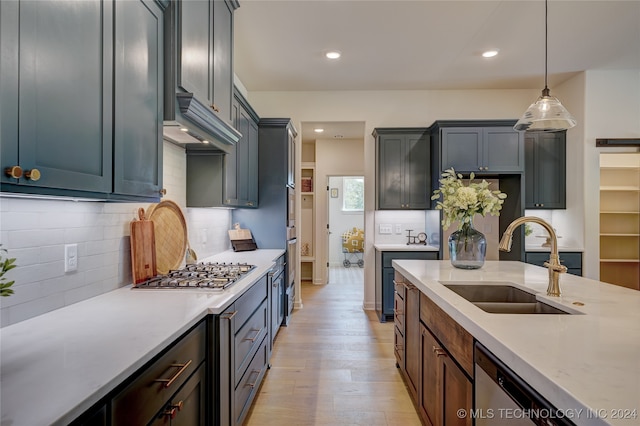 kitchen featuring pendant lighting, sink, decorative backsplash, light wood-type flooring, and appliances with stainless steel finishes