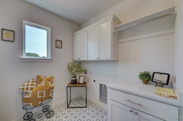 clothes washing area featuring hookup for an electric dryer and cabinets