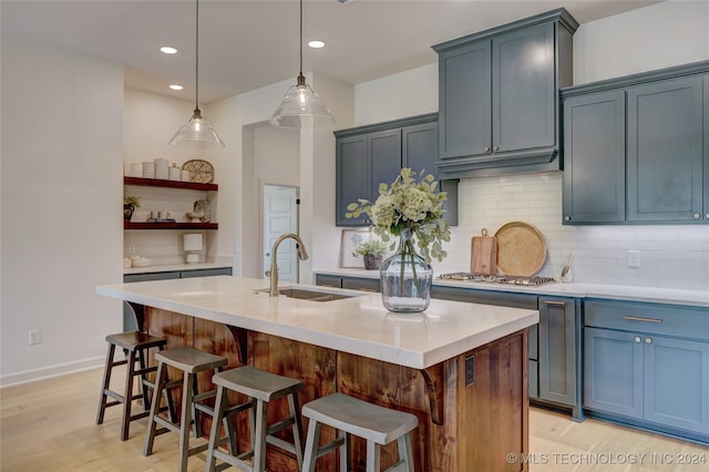 kitchen featuring sink, light wood-type flooring, and a kitchen island with sink