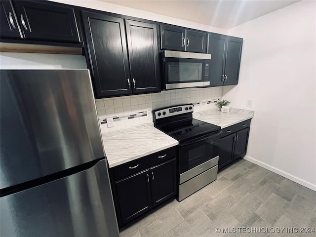 kitchen with appliances with stainless steel finishes, backsplash, and light hardwood / wood-style flooring