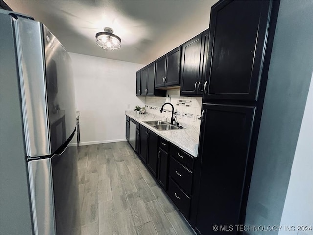 kitchen with decorative backsplash, sink, appliances with stainless steel finishes, and light hardwood / wood-style flooring