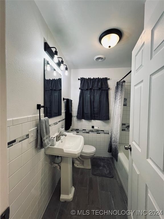 full bathroom with sink, toilet, shower / bath combo with shower curtain, and tile walls