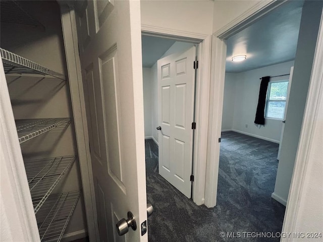 hallway with dark colored carpet