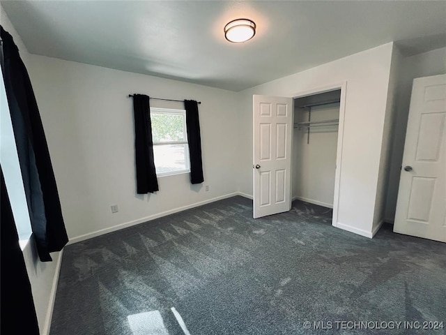 unfurnished bedroom with dark colored carpet and a closet