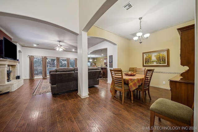 dining area with ceiling fan with notable chandelier, crown molding, and dark wood-type flooring