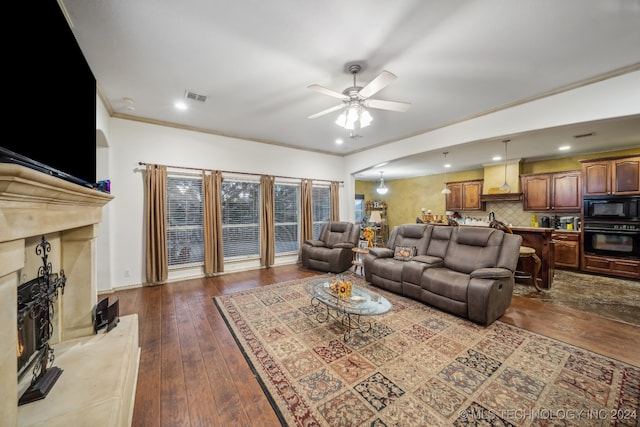 living room featuring ceiling fan, a fireplace, dark hardwood / wood-style flooring, and crown molding