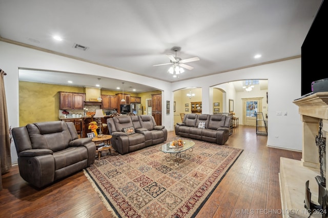 living room featuring hardwood / wood-style floors, ceiling fan with notable chandelier, and crown molding