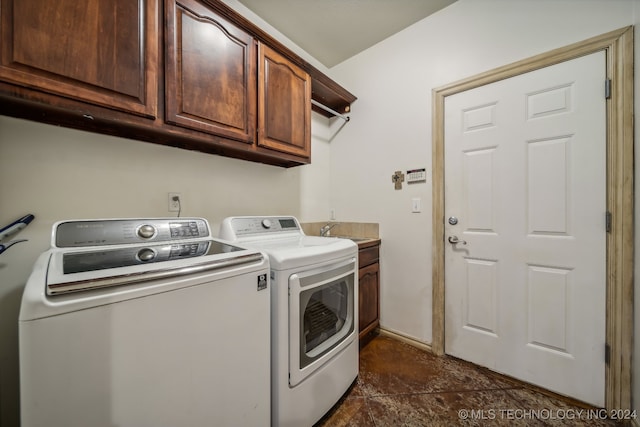 laundry room featuring washer and dryer, dark tile patterned floors, and cabinets