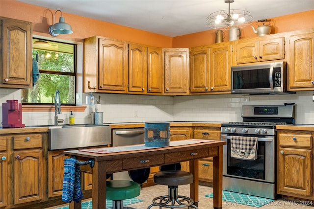 kitchen featuring sink, appliances with stainless steel finishes, a notable chandelier, pendant lighting, and backsplash