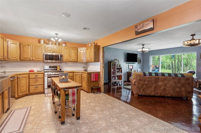 kitchen with an inviting chandelier, appliances with stainless steel finishes, light tile patterned flooring, and decorative backsplash