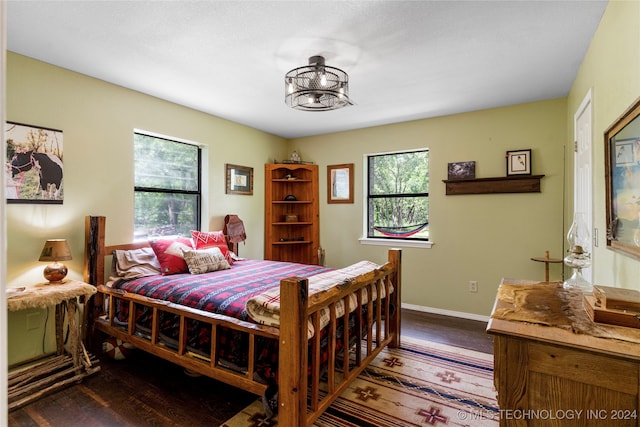 bedroom with multiple windows and dark hardwood / wood-style floors