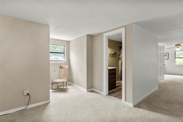 corridor featuring light colored carpet and a textured ceiling