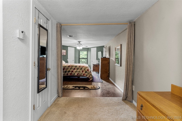 carpeted bedroom featuring ceiling fan and a textured ceiling