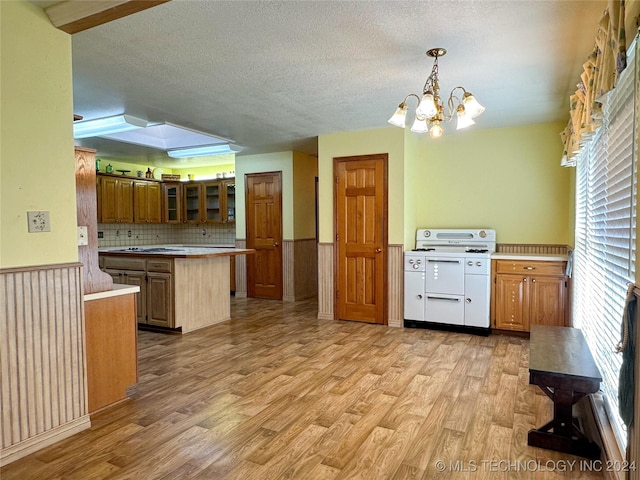 kitchen with light hardwood / wood-style floors, kitchen peninsula, backsplash, decorative light fixtures, and a chandelier