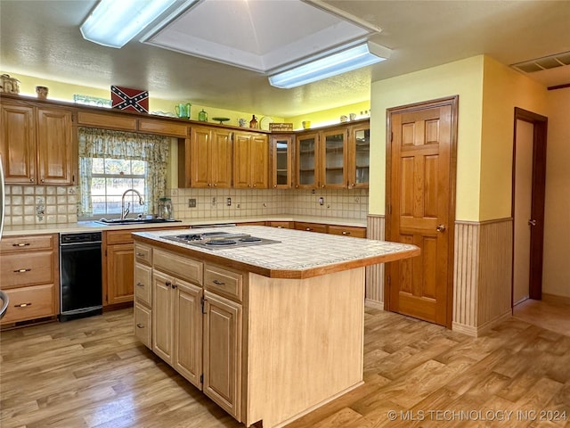 kitchen featuring light hardwood / wood-style floors, tile counters, a center island, stainless steel gas cooktop, and sink