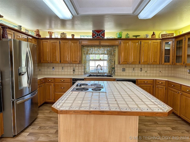 kitchen with appliances with stainless steel finishes, tile counters, and a kitchen island