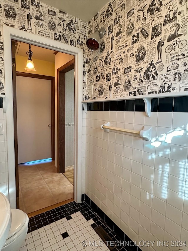 bathroom with tile patterned floors, toilet, and tile walls