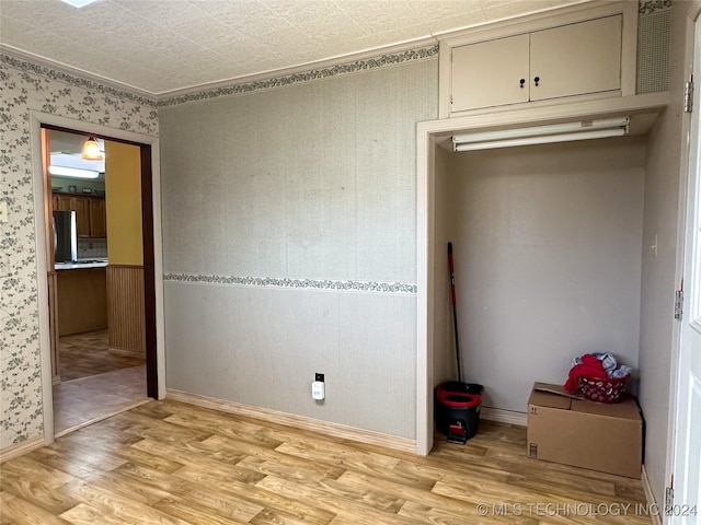 unfurnished bedroom with stainless steel fridge, ornamental molding, and light hardwood / wood-style flooring