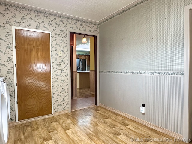 interior space featuring stainless steel fridge with ice dispenser, ornamental molding, and hardwood / wood-style floors