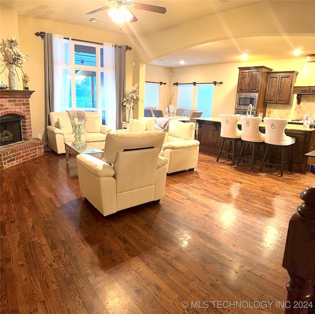 living room with dark hardwood / wood-style floors, ceiling fan, and a fireplace