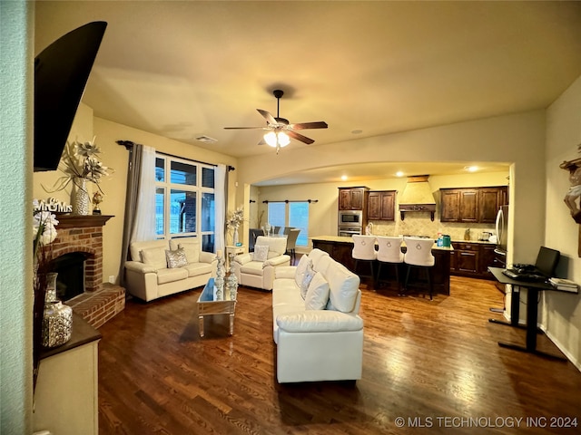 living room featuring a fireplace, wood-type flooring, and ceiling fan