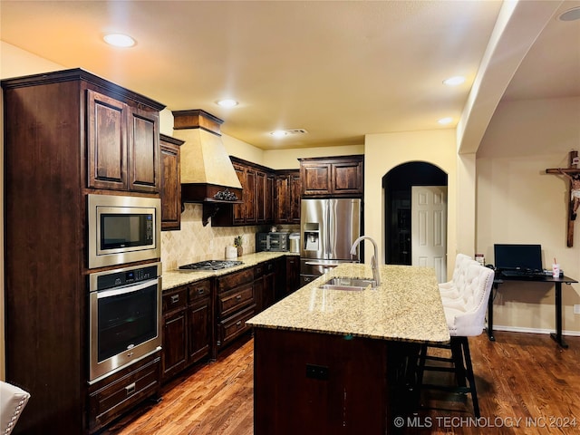 kitchen with hardwood / wood-style flooring, sink, stainless steel appliances, and a kitchen island with sink