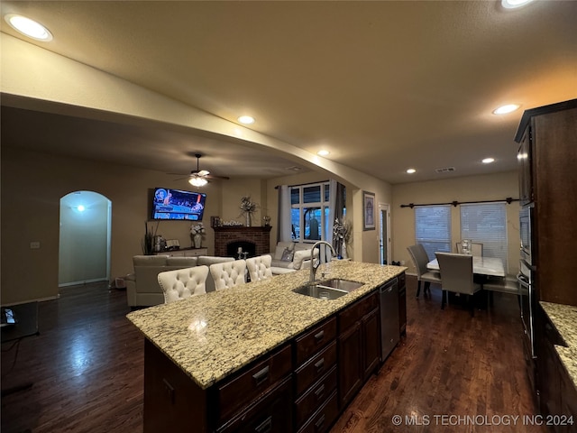 kitchen with ceiling fan, dark hardwood / wood-style floors, a kitchen island with sink, and sink