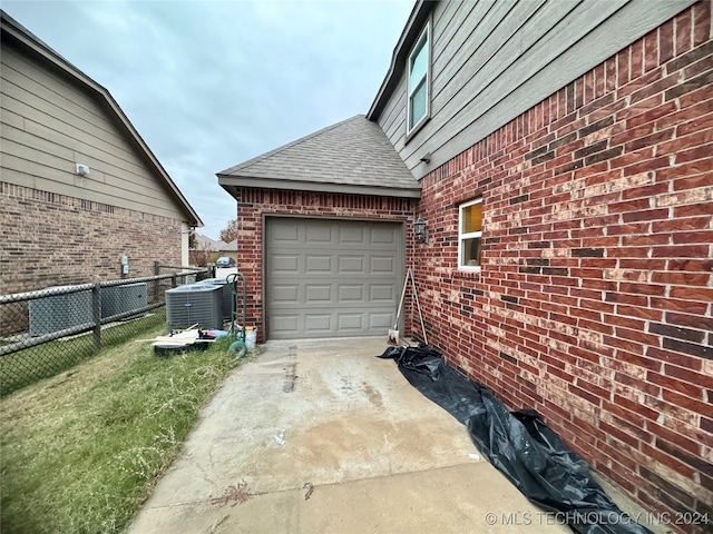 garage with central AC unit and a lawn