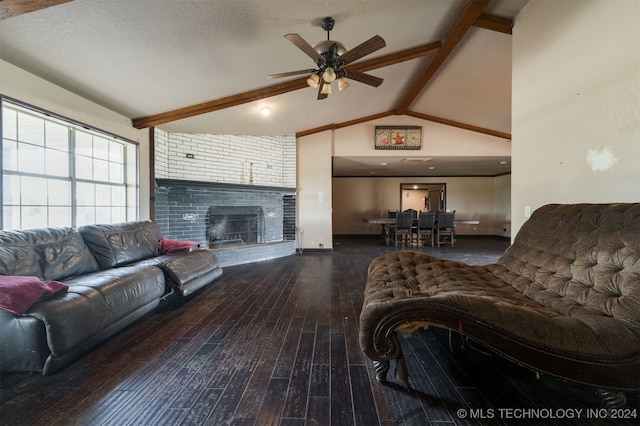 living room featuring a brick fireplace, a textured ceiling, ceiling fan, dark wood-type flooring, and beam ceiling