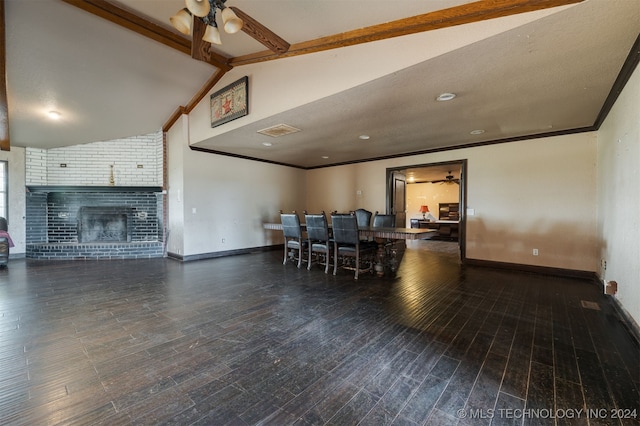 dining area featuring ceiling fan, lofted ceiling with beams, dark hardwood / wood-style floors, and a brick fireplace