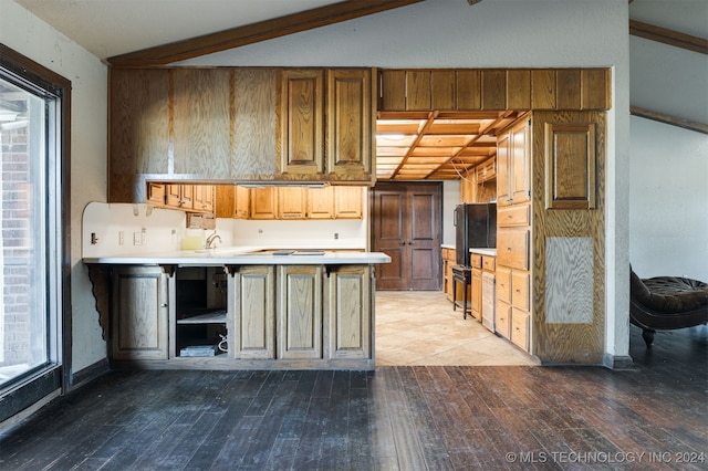 kitchen featuring vaulted ceiling with beams, kitchen peninsula, sink, and light hardwood / wood-style flooring