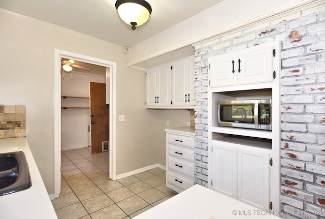 kitchen featuring crown molding, white cabinets, light tile patterned flooring, and ceiling fan