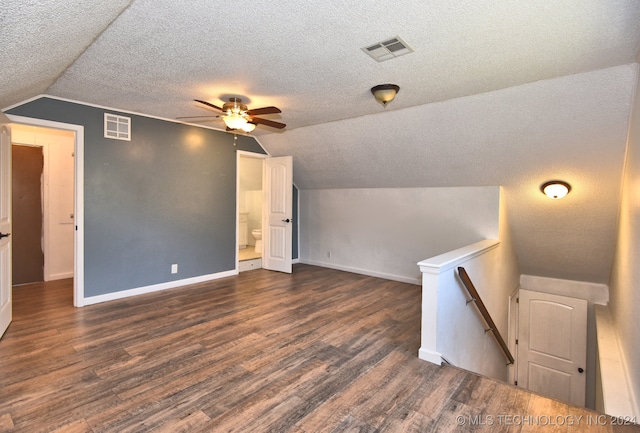 additional living space with dark hardwood / wood-style flooring, lofted ceiling, and a textured ceiling