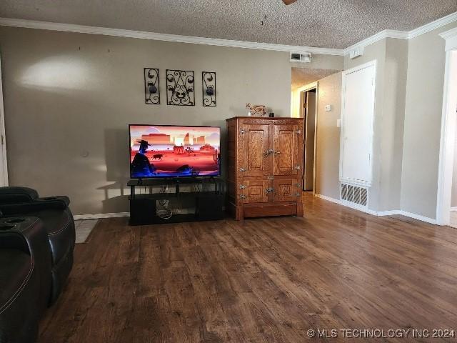 living room featuring wood-type flooring, a textured ceiling, and ornamental molding