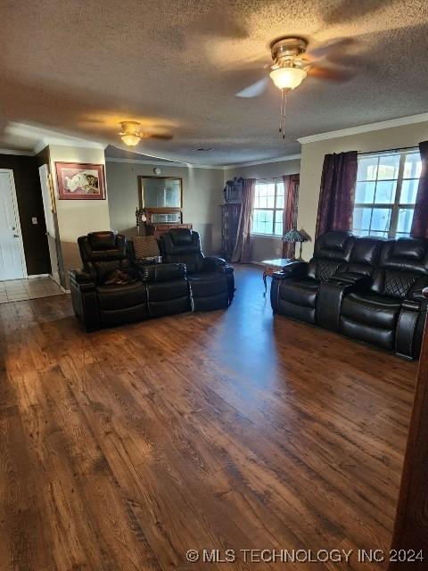 living room with ceiling fan, dark hardwood / wood-style floors, a textured ceiling, and ornamental molding