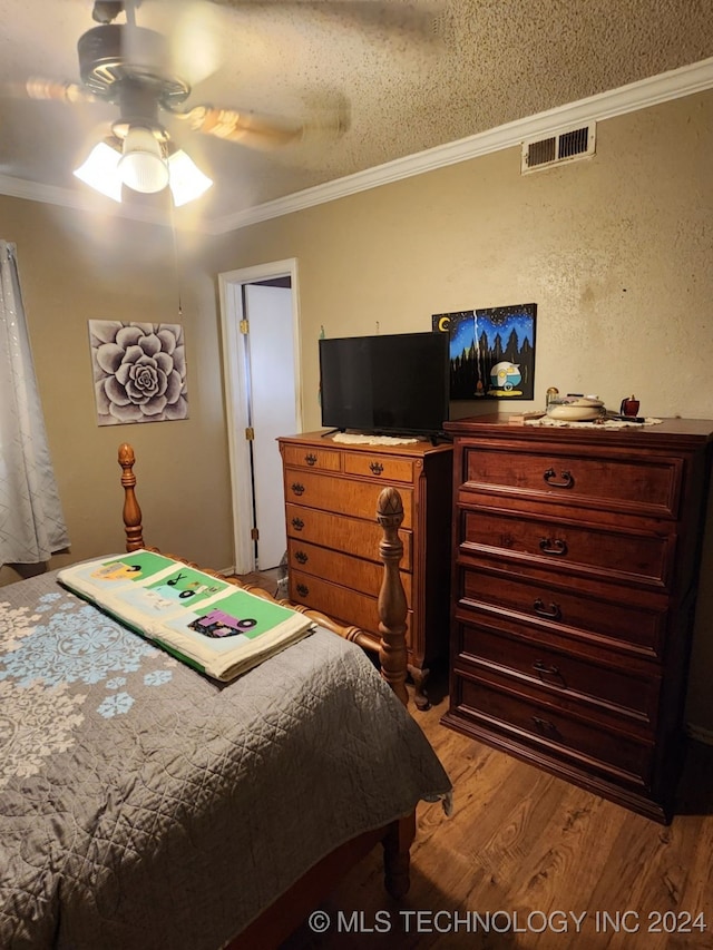 bedroom featuring ceiling fan, crown molding, wood-type flooring, and a textured ceiling